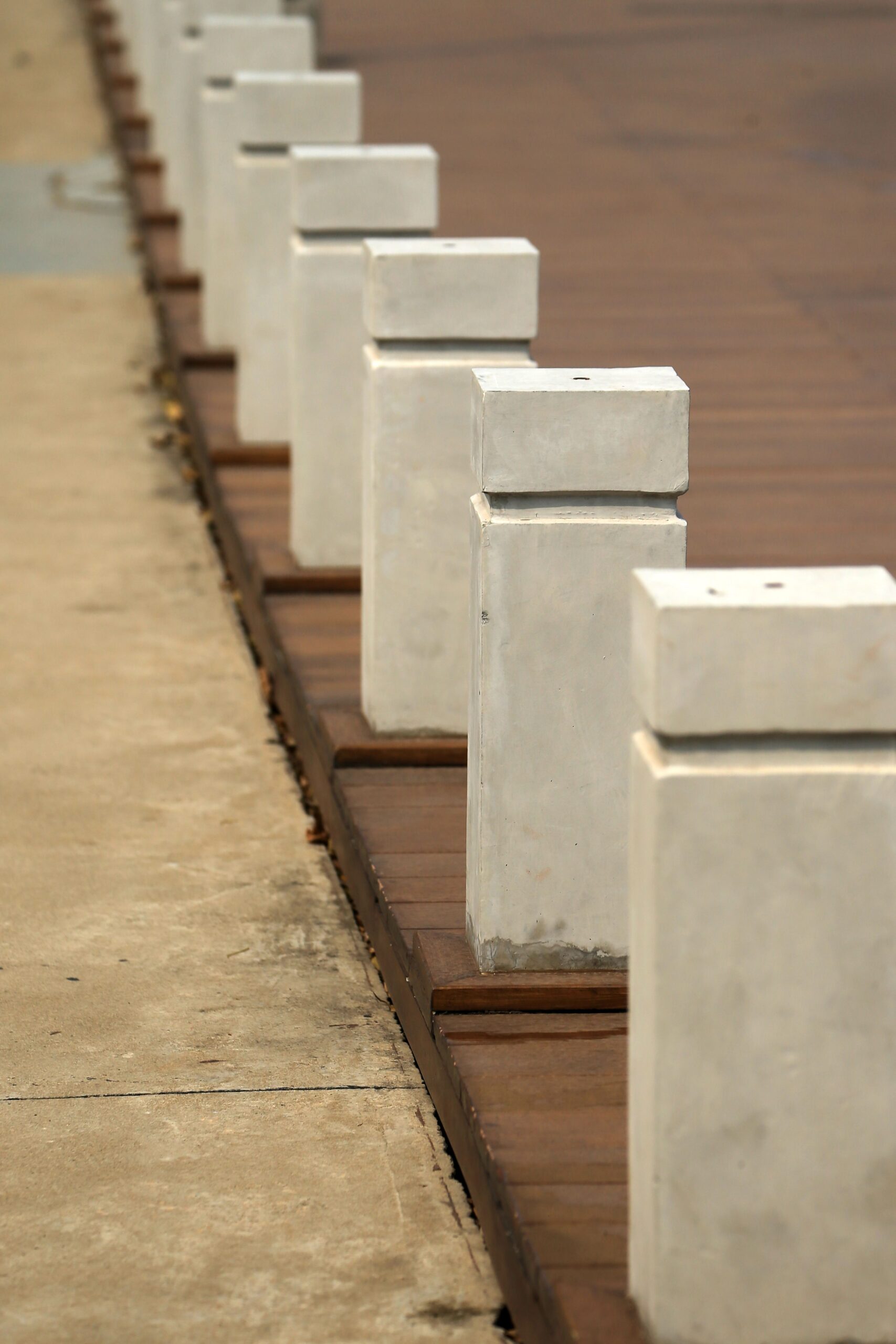 A row of white concrete bollards placed alongside a pavement, showcasing perspective.