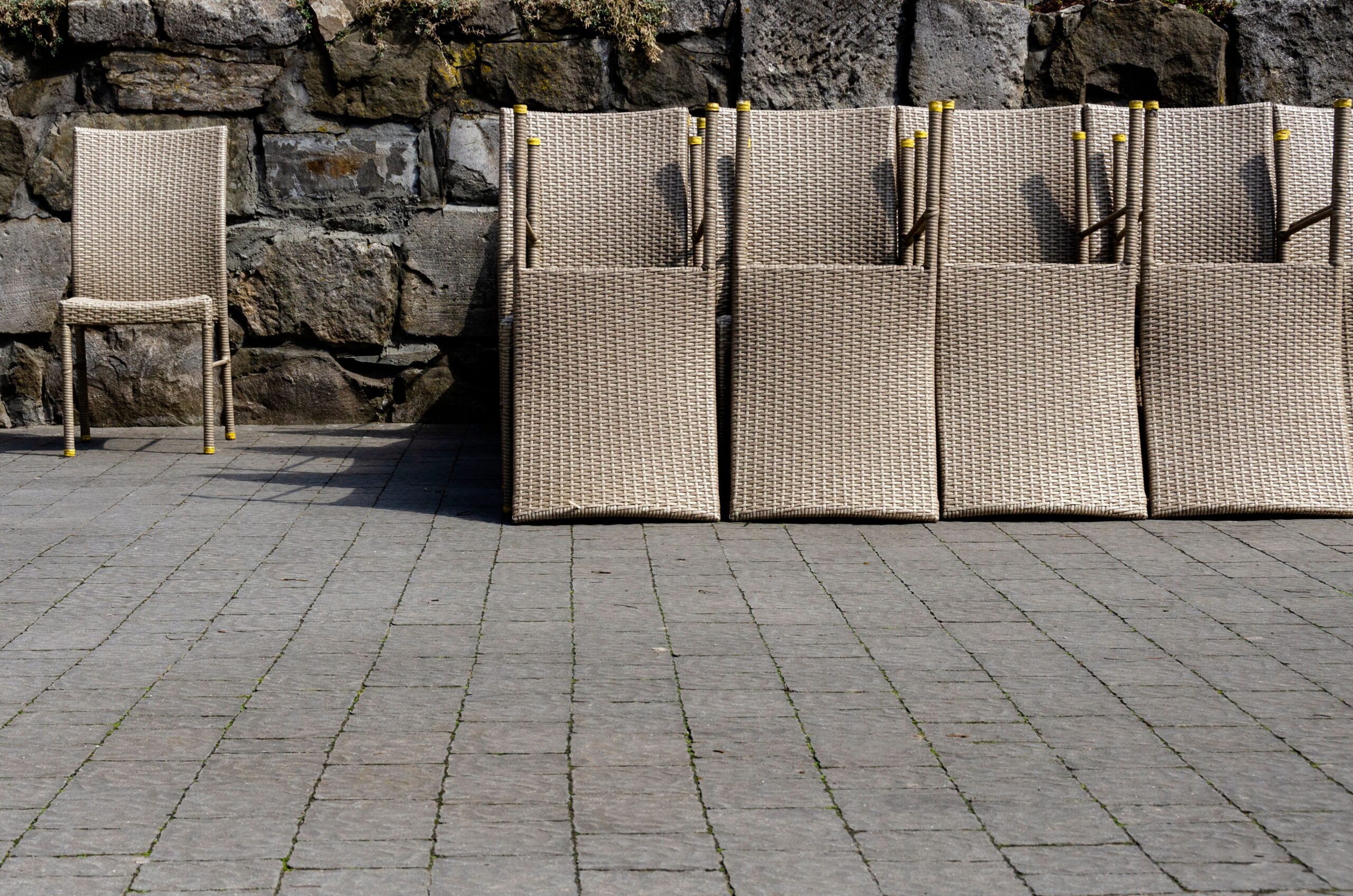 Wicker outdoor chairs arranged against a rustic stone wall in Lviv, Ukraine.