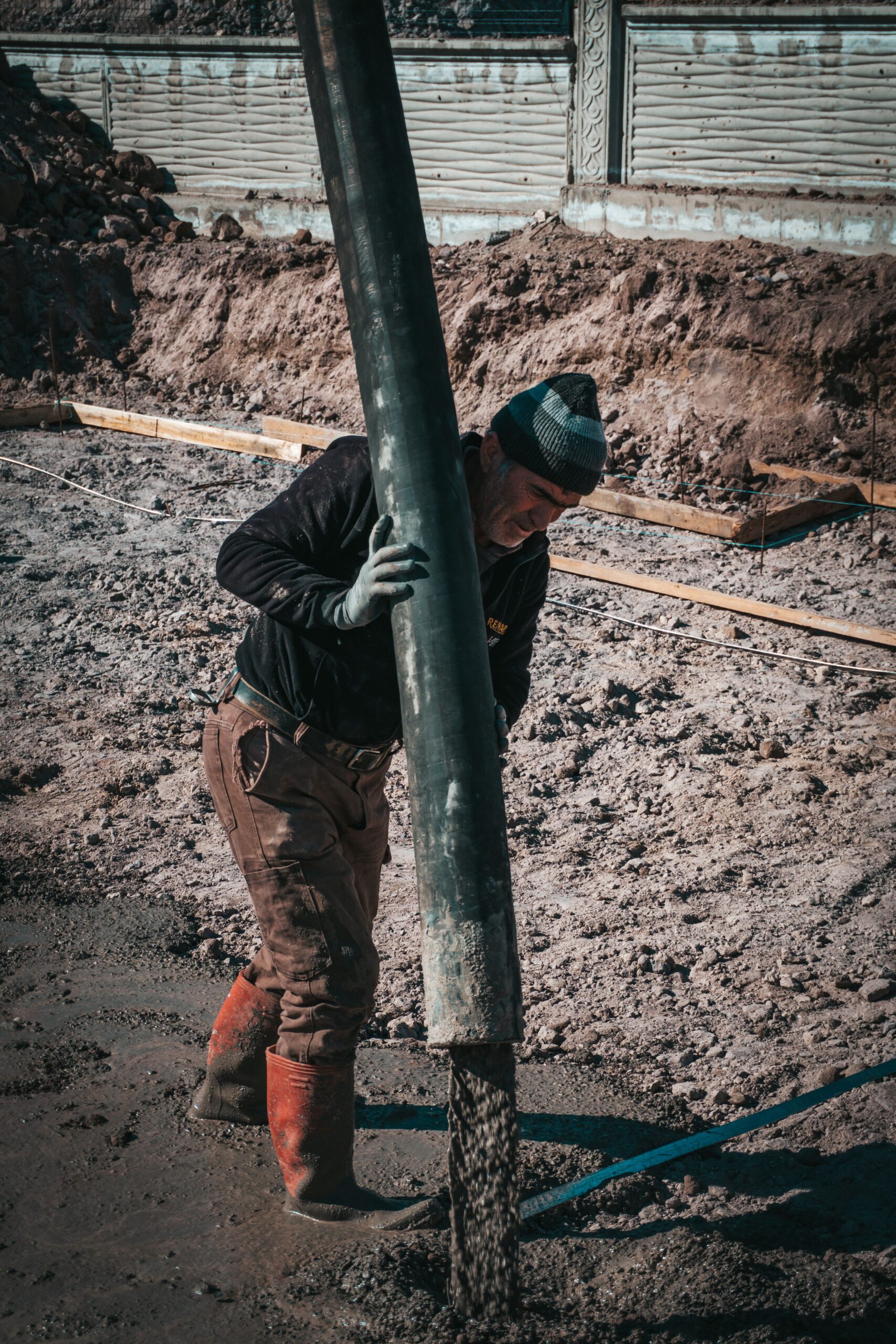 A dedicated worker in Türkiye operates a concrete pump at an outdoor construction site.
