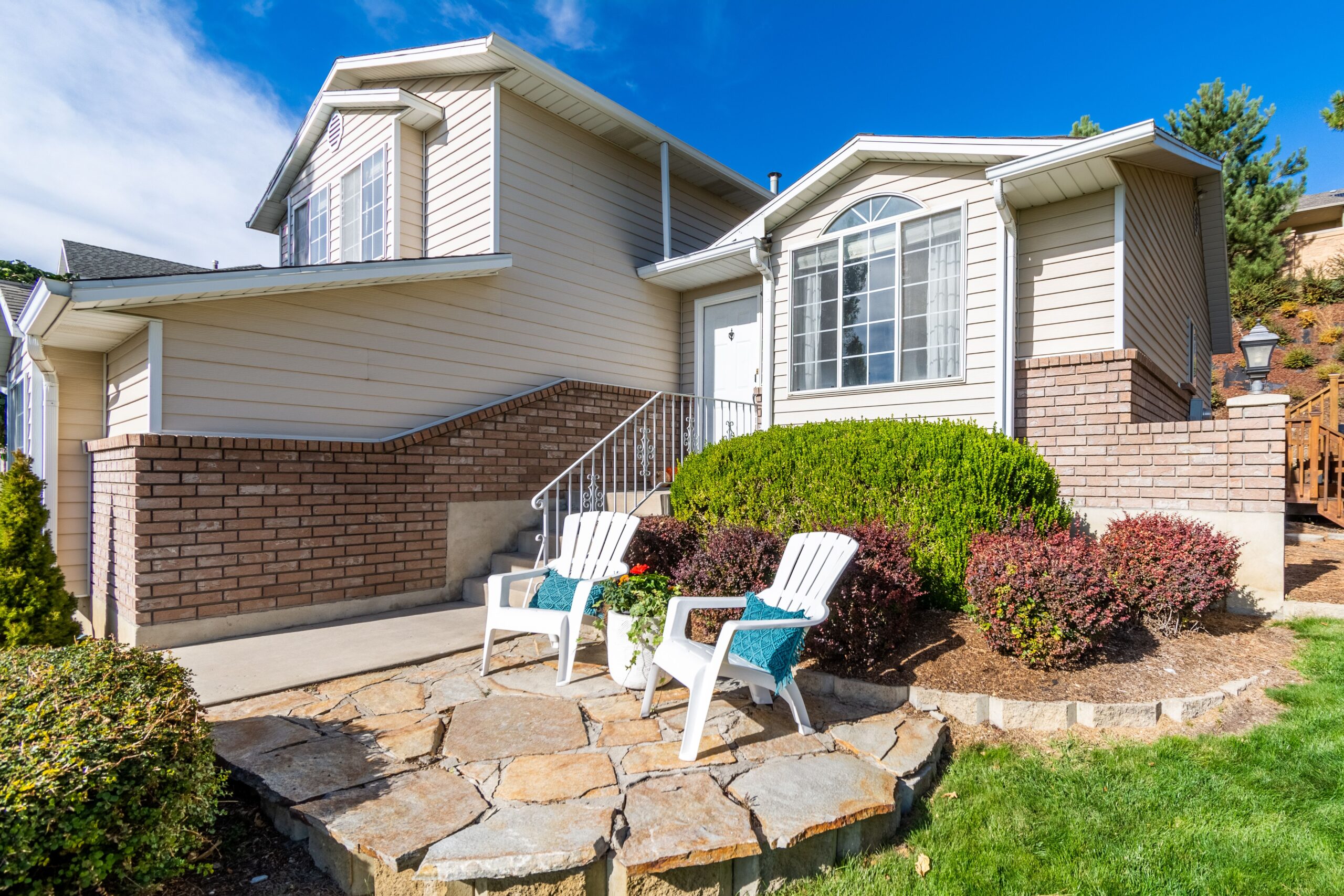 Elegant suburban house exterior with porch and seating area in bright daylight.