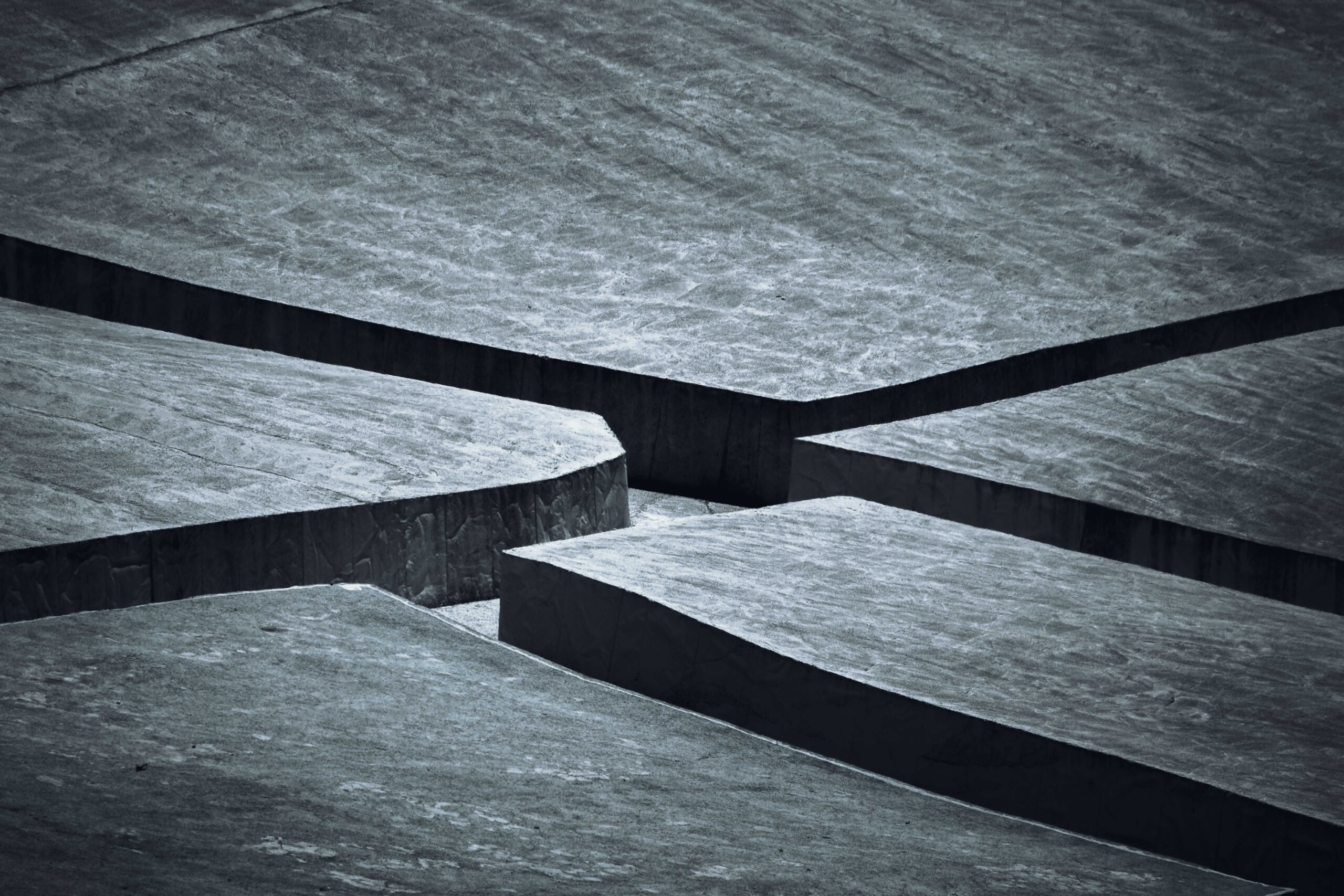 A complex gray textured surface featuring sharp, intersecting lines in a minimalist abstract style.